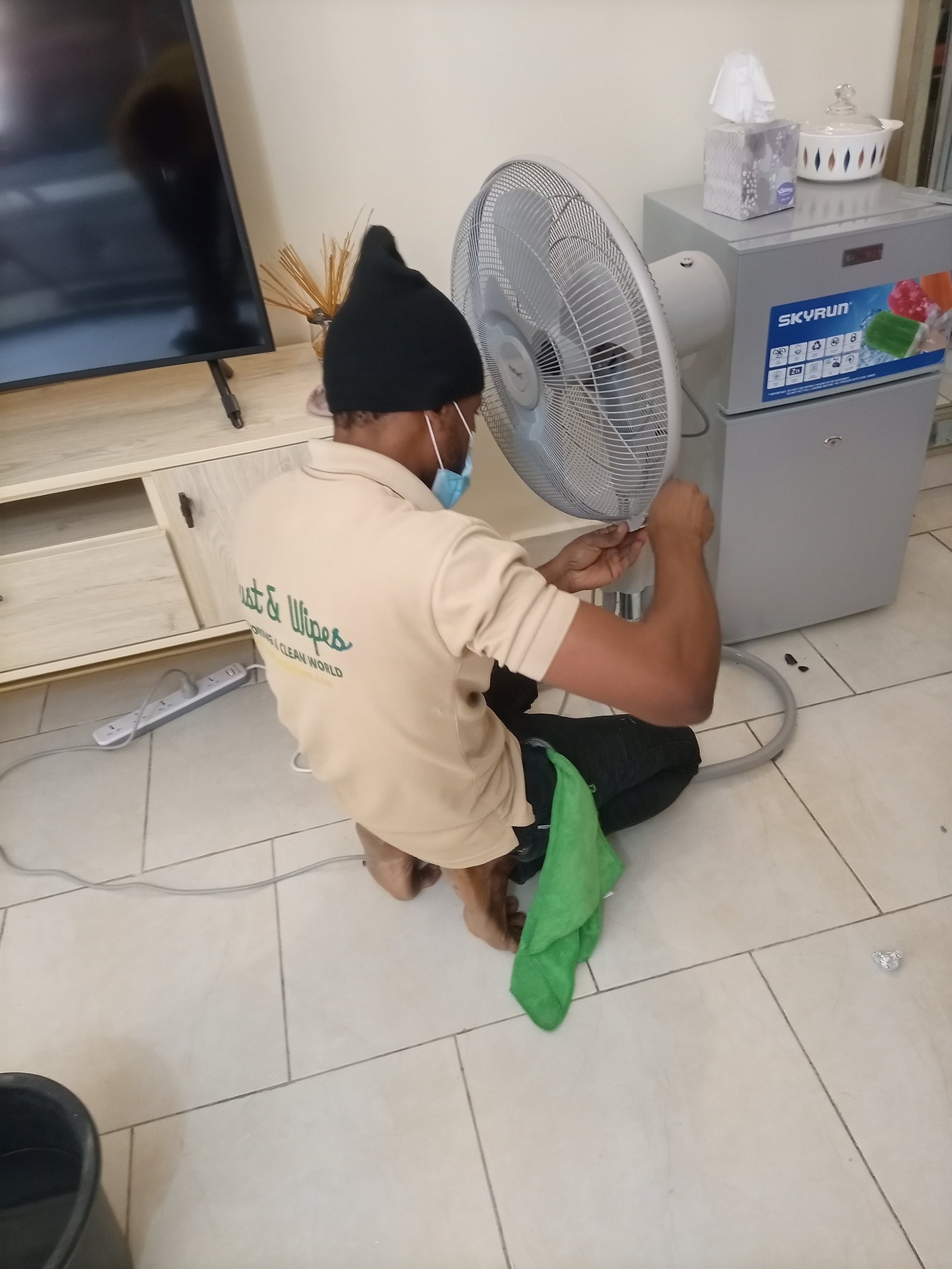 Staff cleaning ceiling fan in residential home in Abuja
